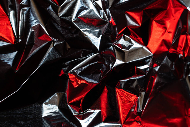 Crumpled aluminum foil, red neon glare on metal surface - Foto, afbeelding