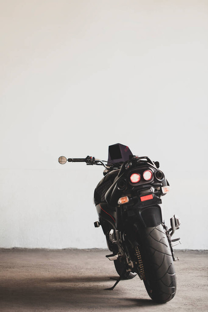 Черный мотоцикл на фоне подземной серой стены в студии
. - Фото, изображение