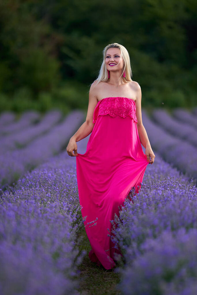 Young blonde woman in pink dress in a lavender field with various poses - Fotografie, Obrázek