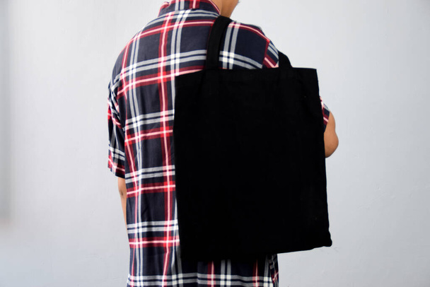 Man Holding Black Blank Tote Bag met behulp van voor mockup ontwerp - Foto, afbeelding