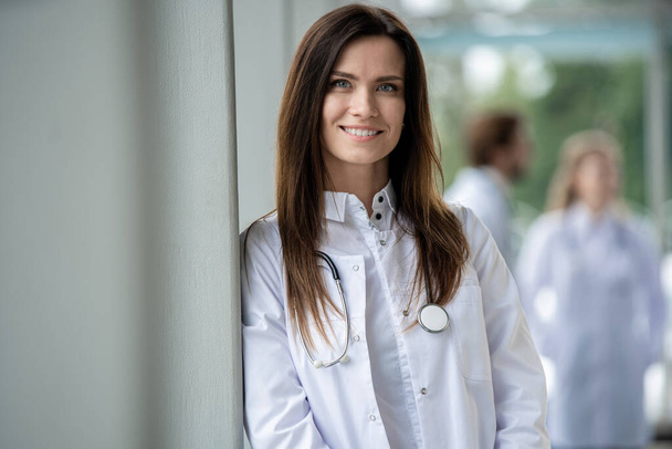 Portrait of young woman doctor with white coat standing in hospital. - Foto, afbeelding