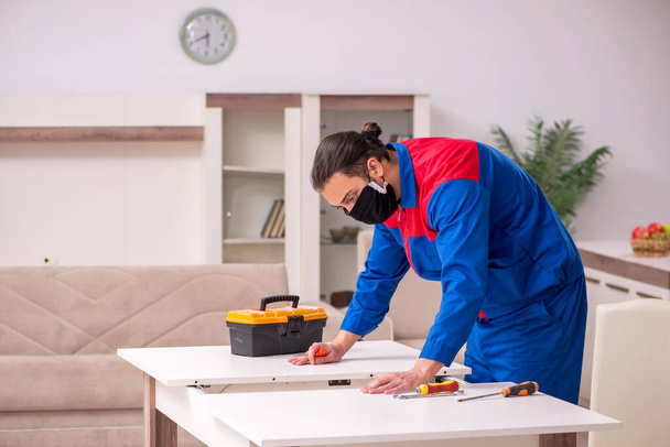 Jovem carpinteiro trabalhando dentro de casa durante a doença pandêmica
 - Foto, Imagem