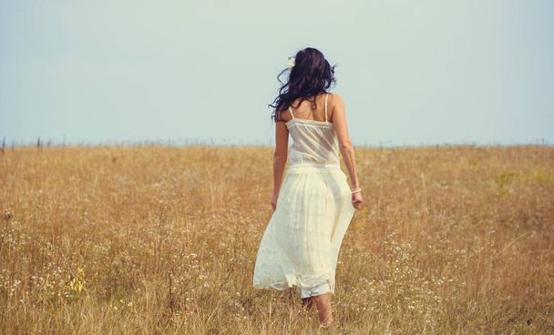 Romantic portrait in vintage tones and texture woman in a lacy clothes standing in the  field and enjoying herself and nature. The concept of self love and harmony with the environment - Photo, image