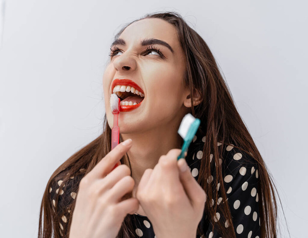 Dental concept. Young girl with red lips brushing teeth with toothbrush. Cropped photo. - Foto, Bild