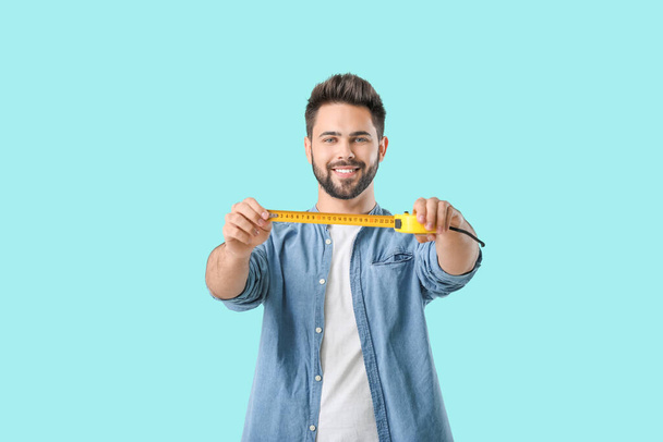 Young man with measuring tape on color background - Φωτογραφία, εικόνα