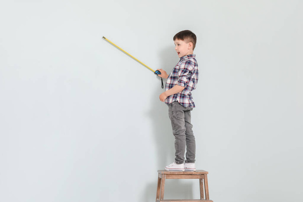 Little boy with measuring tape on grey background - Foto, afbeelding