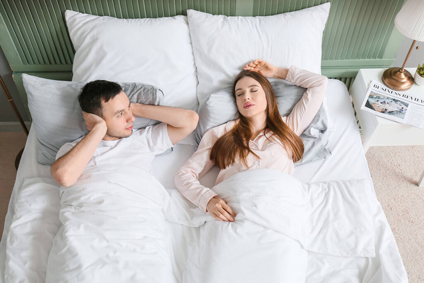 Young irritated man in bed with snoring wife - Foto, Imagen