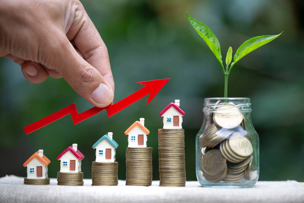 Büyüyen ev minyatürünün ve cam şişelerde yetişen ağaçların el ele tutuşma grafiği. Emlak yatırımı ve ev kredisi finansal konsepti, yatırım mülkü, gayrimenkul, tasarruf. - Fotoğraf, Görsel