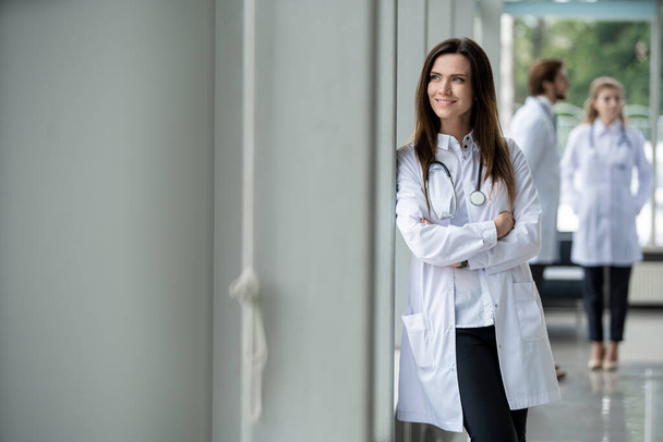 Portrait of young woman doctor with white coat standing in hospital. - Foto, Bild