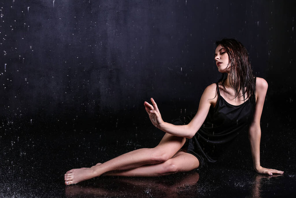 Gyönyörű fiatal nő és csöpögő víz sötét háttér - Fotó, kép