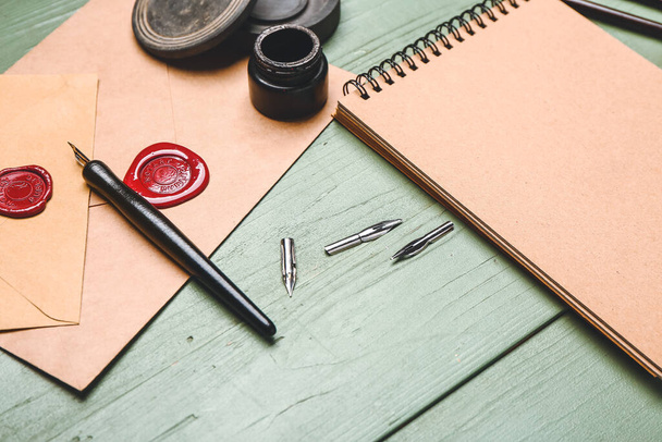 Notebook, nib pen, envelopes and ink on table - Фото, зображення
