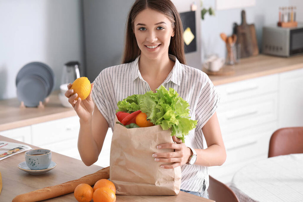 Young woman with fresh products from market at home - Foto, Bild