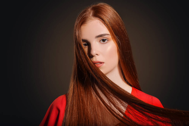 Mooie jonge roodharige vrouw op donkere achtergrond - Foto, afbeelding