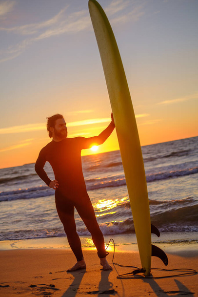 Γενειοφόρος σέρφερ στην παραλία κατά τη διάρκεια του ηλιοβασιλέματος - Φωτογραφία, εικόνα