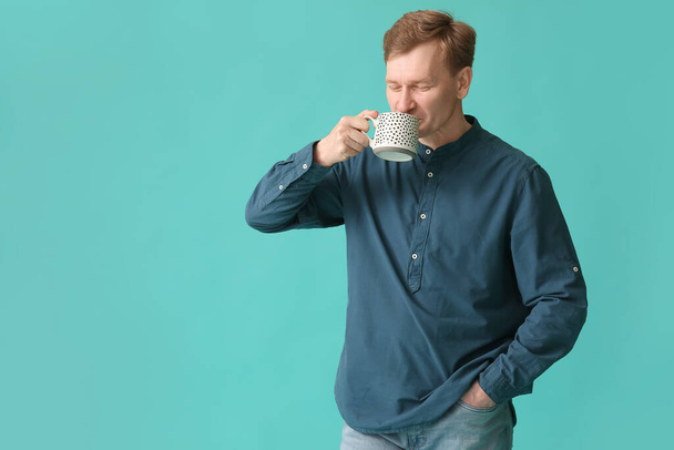 Handsome man with cup of tea on color background - Fotoğraf, Görsel