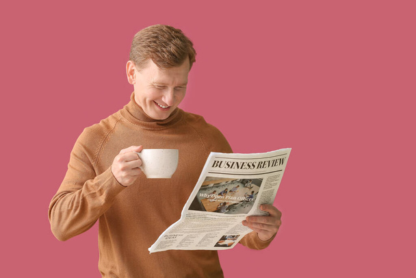 Handsome man with cup of tea and newspaper on color background - Foto, afbeelding