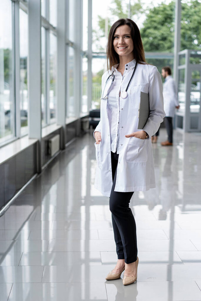 Portrait of young woman doctor with white coat standing in hospital. - Foto, Imagen