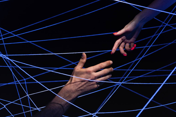 Образ чоловічої та жіночої руки серед ниток у неоновому світлі
 - Фото, зображення