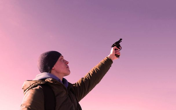 Young man in a hat shoots a pistol at the top - Fotó, kép
