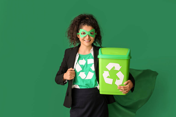 Woman dressed as eco superhero with trash bin on color background - Photo, image