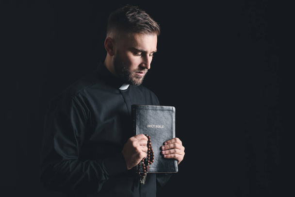 Junger Priester betet vor dunklem Hintergrund zu Gott - Foto, Bild