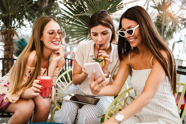 Три красивых друга в кафе с помощью цифрового планшета и телефона и весело
 - Фото, изображение