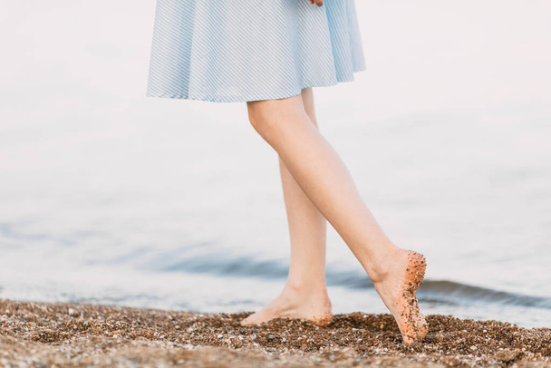 Großaufnahme weiblicher Füße, eine Frau, die an einem Sandstrand spaziert und Fußspuren im Sand hinterlässt. Sommerurlaub, Meer - Foto, Bild