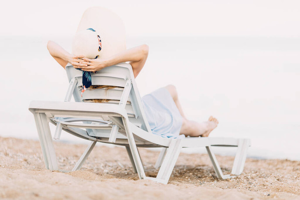 relaxing girl in a summer hat, resting on a sandy beach, lies on a chaise longue. Summer vacation, travel - Fotoğraf, Görsel
