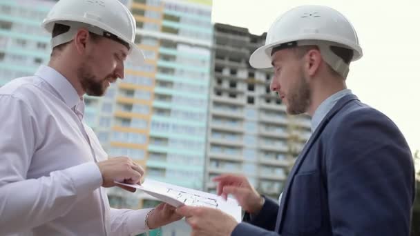 Two construction engineers discussing a construction plan - Imágenes, Vídeo