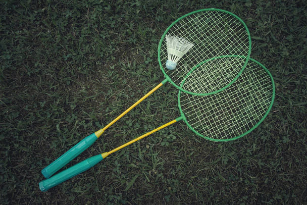 Ракетки бадминтона с шаттлом на зеленой траве, летние активные игры
 - Фото, изображение