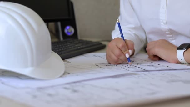 Ingeniero de construcción toma notas sobre los dibujos sentados en la oficina
 - Metraje, vídeo