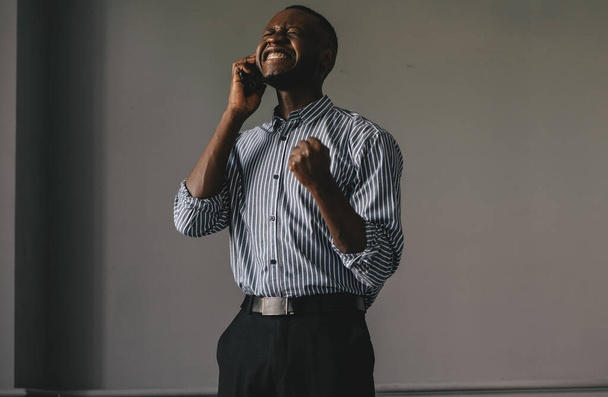 black guy on a gray background talking on the phone happy learns the good news - Valokuva, kuva