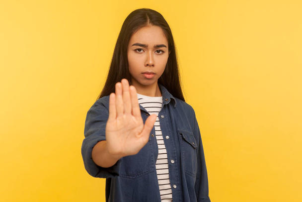 No, forbidden to do! Portrait of upset girl in denim shirt showing stop gesture, rejection prohibition hand sign, warning of troubles, declining conflict and problems. indoor studio shot, isolated - Photo, Image