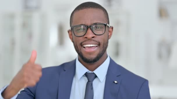 Portret atrakcyjnego afrykańskiego biznesmena pokazującego kciuki w górę  - Materiał filmowy, wideo