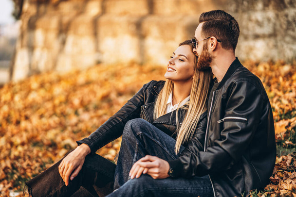 Portrait of a young loving couple, sitting in autumn leaf and enjoying nature. Love story. - Fotografie, Obrázek
