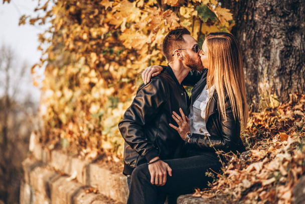 Sunny portrait of a young loving couple walking in the autumn park. They hug and smile, enjoy a walk. - Foto, afbeelding