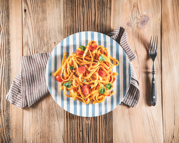 Pasta with tomato sauce on wooden table. Top view delicious tagliatelle. Vintage concept, retro style - Fotó, kép