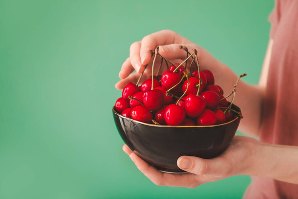 Woman with bowl of sweet cherry on color background, closeup - Foto, Imagem