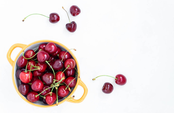 View from above on the bowl with fresh ripe red cherries on a white background - Photo, Image