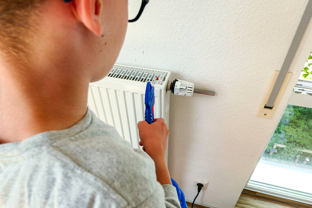 Enfant nettoie les radiateurs dans sa chambre avec le pistolet à air comprimé - Photo, image