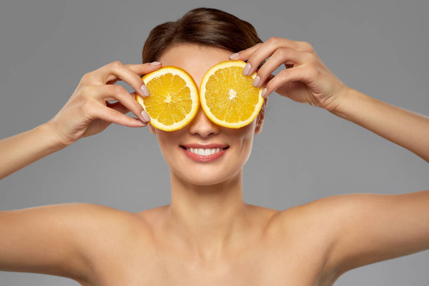 beautiful woman making eye mask of orange slices - Photo, image
