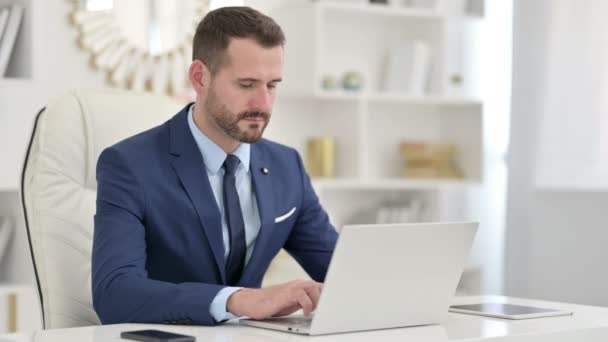 Serious Businessman using Laptop in Office  - Кадри, відео
