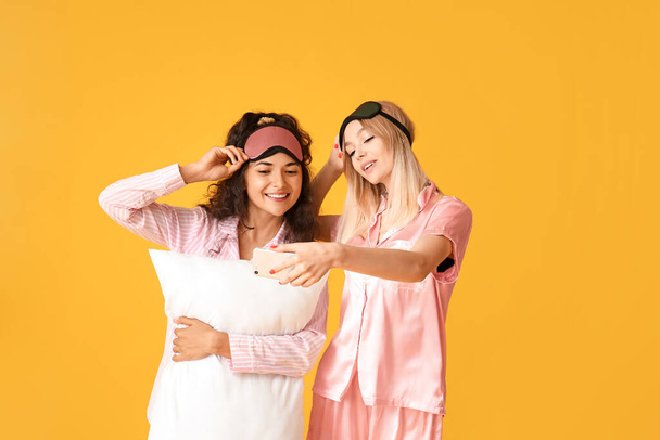 Красивые молодые женщины в пижаме делают селфи на цветном фоне
 - Фото, изображение