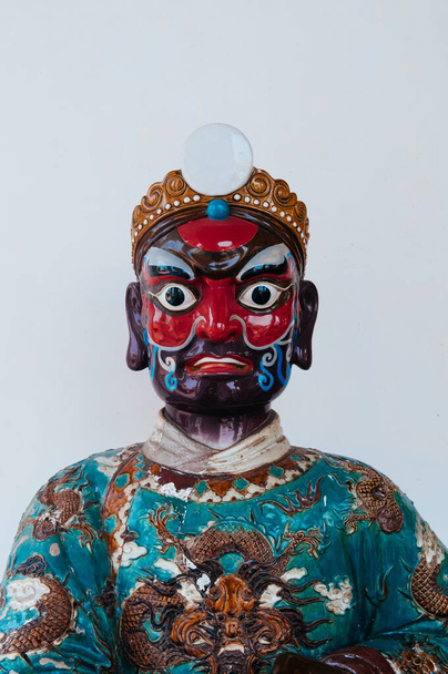 Farbig bemaltes Gesicht einer antiken chinesischen Schiffsballaststein-Krieger-Keramikpuppe im Tempel Wat Ratchaorasaram, Bangkok - Foto, Bild
