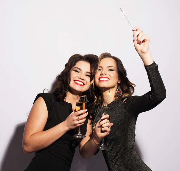 Beautiful young girls ready for a party, laughing and holding sparklers - Foto, Imagem