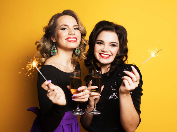 Beautiful young girls ready for a party, laughing and holding sparklers - Photo, Image