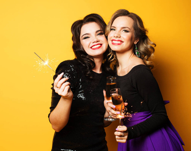 Beautiful young girls ready for a party, laughing and holding sparklers - Fotó, kép