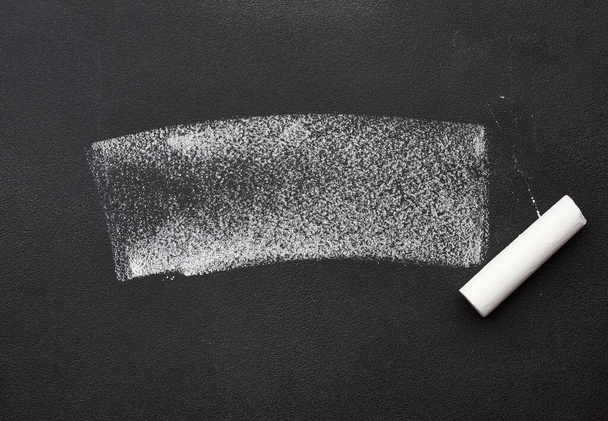 weiße Kreideprobe auf einer schwarzen Kreidetafel und einem Stück Kreide, Nahaufnahme - Foto, Bild