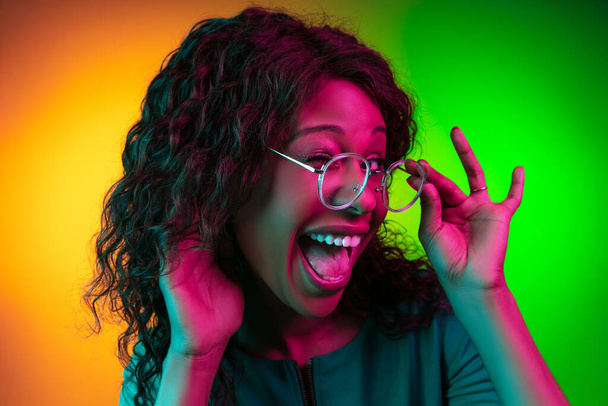 African-american young womans portrait isolated on gradient yellow-green background in neon light - Fotografie, Obrázek