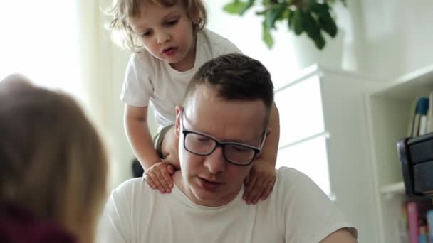 Ένας στοργικός πατέρας μιλάει στην κόρη του κατά τη διάρκεια ενός παιχνιδιού ενώ ο μικρός γιος του σκαρφαλώνει στους ώμους του. Κοντινό πλάνο - Πλάνα, βίντεο